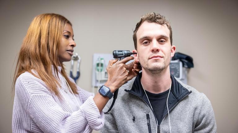 A Duquesne student resident checking a patient's ear